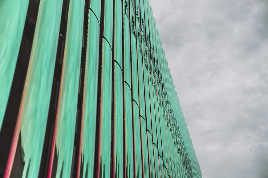 Modern Green Glass Building Facade Against Cloudy Sky