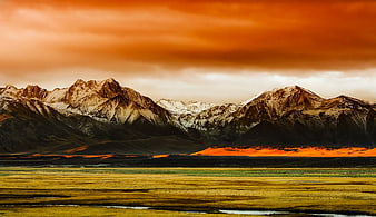 Dramatic sunset over snow-capped mountains and golden valley
