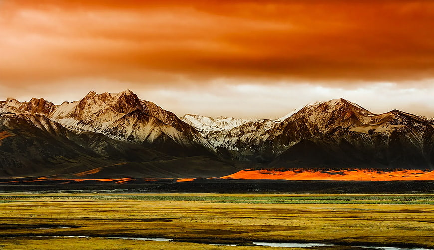Dramatic sunset over snow-capped mountains and golden valley