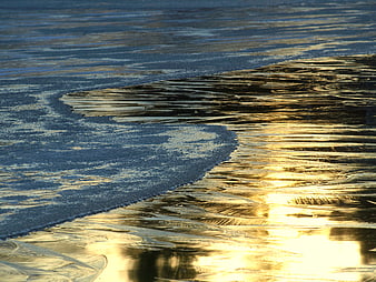 Golden sunlight reflecting on frozen ice and water surface