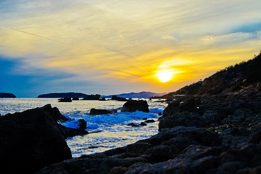 Golden Sunset Over Rocky Coastal Shoreline with Ocean Waves
