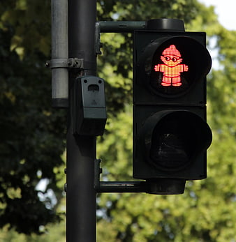 Red pedestrian traffic light signal with standing figure on urban street