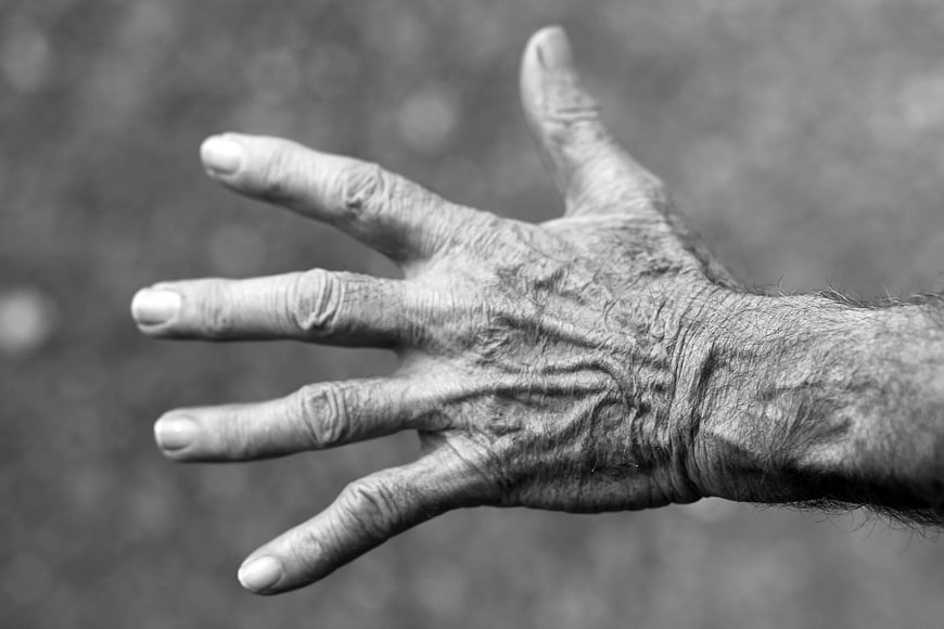 Close-up of wrinkled elderly hand in black and white