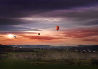Hot Air Balloons Flying Over Rolling Hills at Sunset