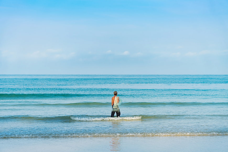 Man Standing in Ocean Waves Looking at Horizon