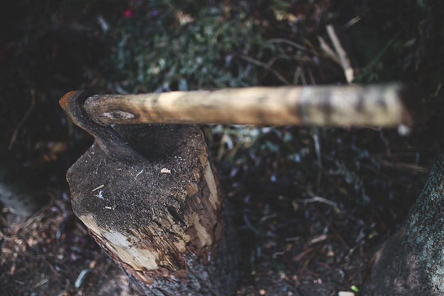 Rusty axe embedded in a wooden stump outdoors