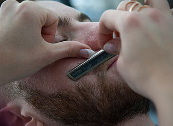 Close-up of straight razor shaving a man's beard
