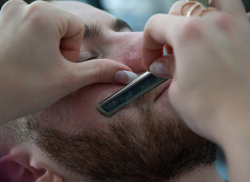 Close-up of straight razor shaving a man's beard