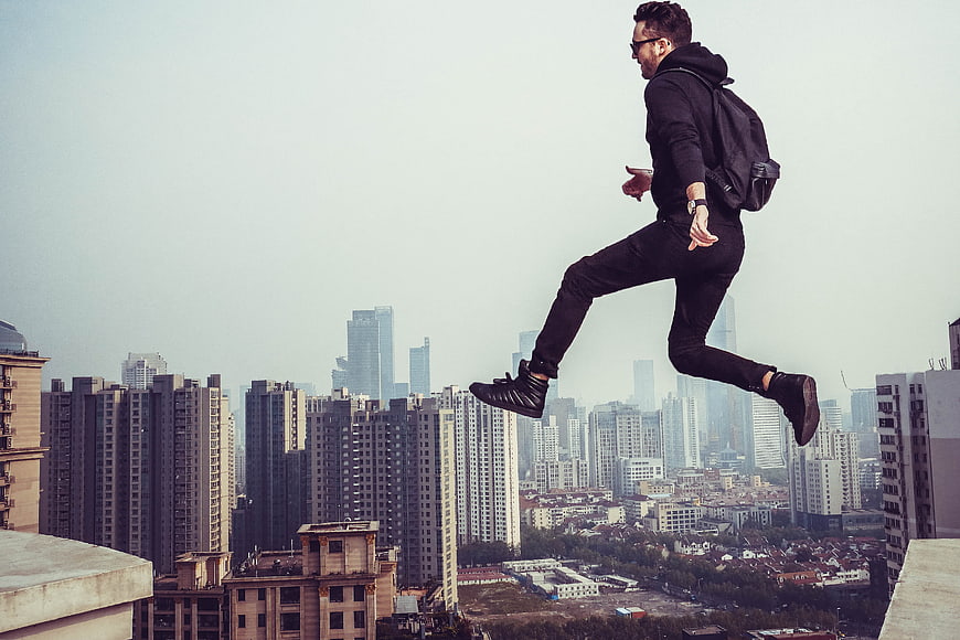 Man jumping on rooftop with city skyline background