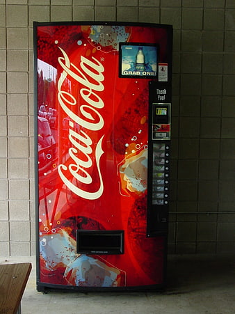 Red Coca-Cola vending machine against brick wall