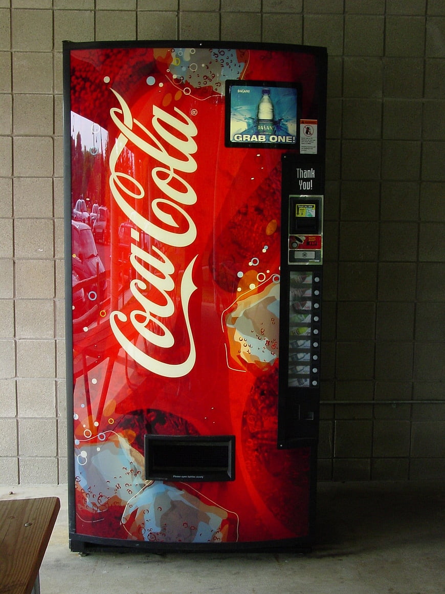 Red Coca-Cola vending machine against brick wall