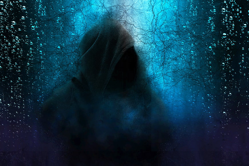 Mysterious hooded figure in dark blue misty atmosphere