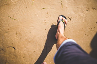 Man Walking on Sandy Beach in Flip Flops