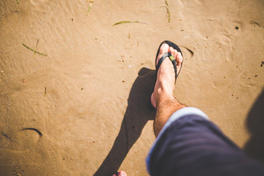 Man Walking on Sandy Beach in Flip Flops