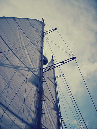 Low angle view of sailboat mast and sails against sky