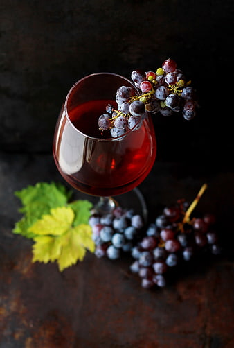 Glass of Red Wine with Grapes and Leaves on Dark Background