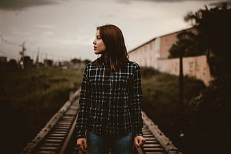 Woman in Plaid Shirt Standing on Railway Tracks