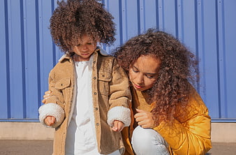 Mother comforting sad child against blue wall