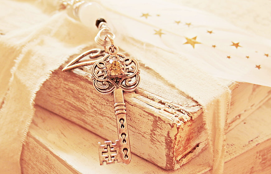 Vintage ornate key on old books with feather and stars