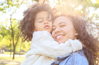 Happy Mother Hugging Daughter in Sunlit Park