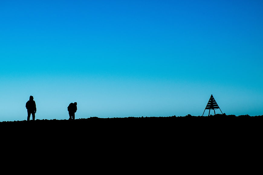 Silhouettes of Hikers on Highland Ridge Against Blue Sky