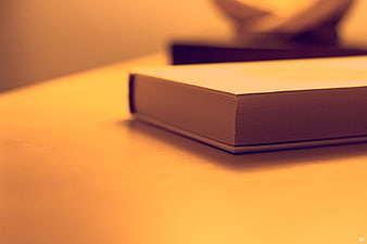 Close-up of a thick book on a wooden desk with warm lighting