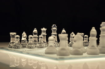 Glass and White Chess Pieces on Reflective Board