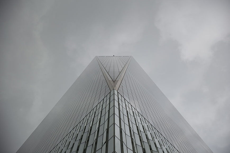 Low angle view of modern skyscraper against cloudy sky