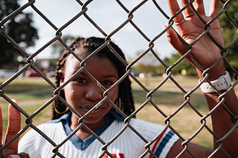 Young Black Woman Behind Chain Link Fence