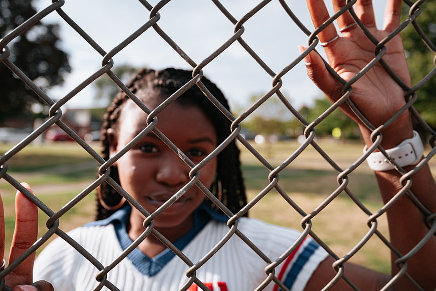 Young Black Woman Behind Chain Link Fence