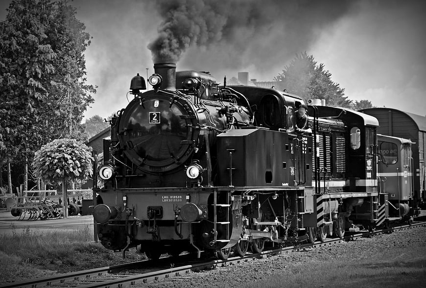 Vintage Steam Locomotive Emitting Smoke on Railroad Tracks