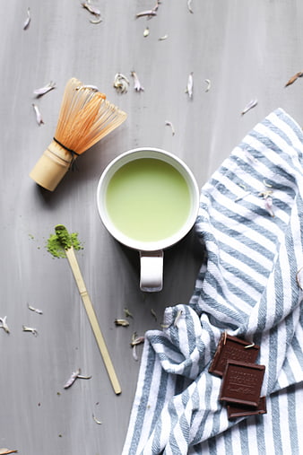 Top view of matcha latte with whisk and chocolate