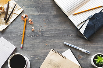 Flat lay of workspace with coffee, pencils, and notebooks