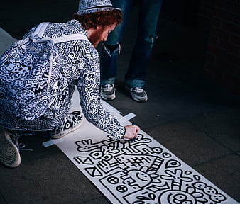 Artist drawing black and white doodle art on pavement