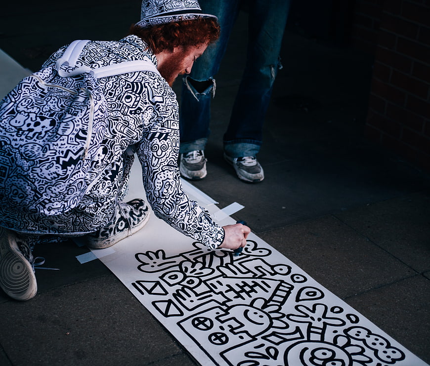 Artist drawing black and white doodle art on pavement