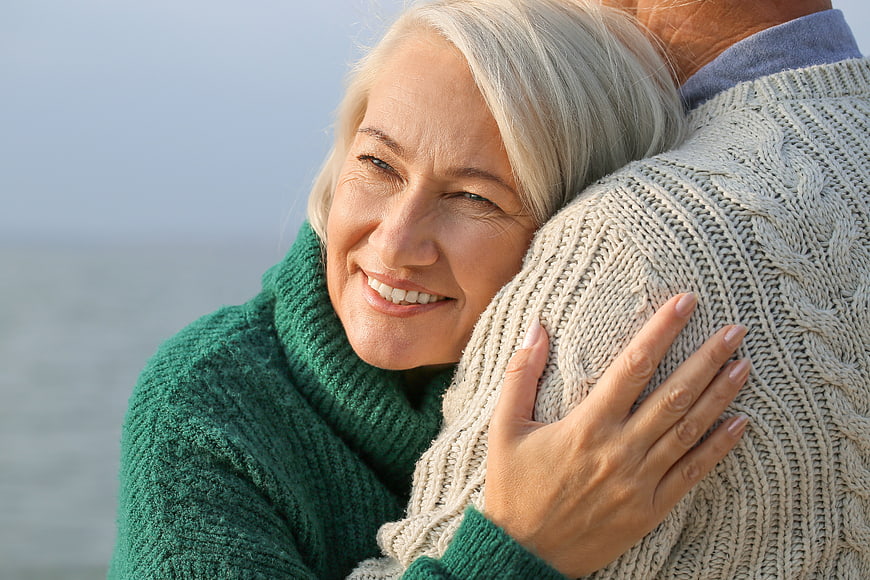 Happy Senior Couple Hugging Outdoors in Knit Sweaters
