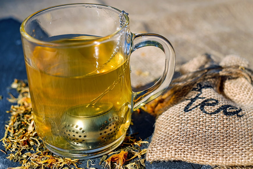 Glass Cup of Herbal Tea with Infuser and Dried Leaves