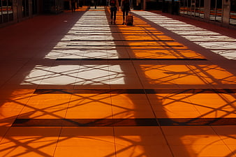 Sunlight shadows on tiled floor with travelers walking