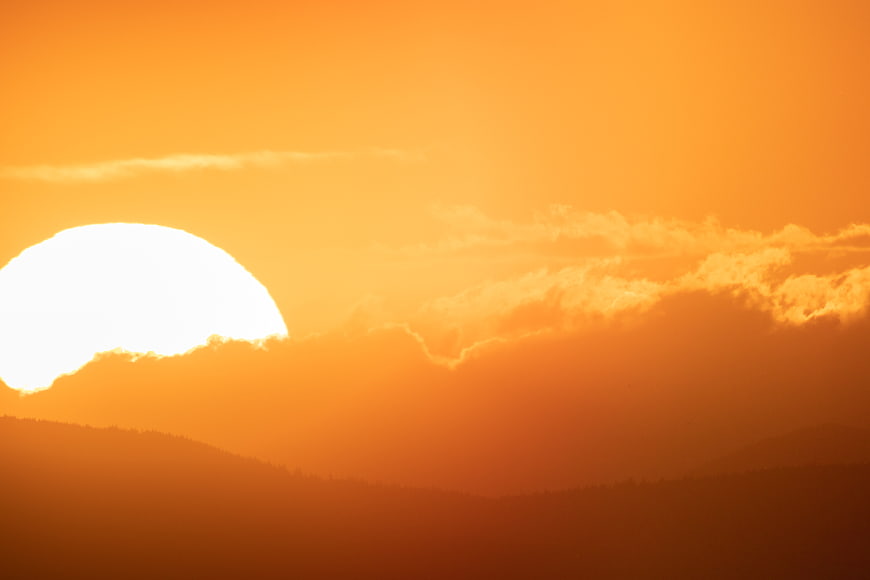 Vibrant Orange Sunset Over Silhouetted Mountain Ranges