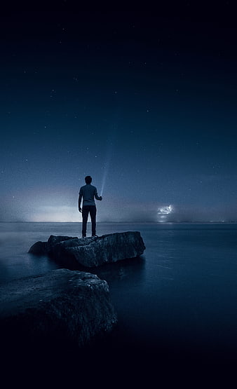 Man standing on rock looking at starry night sky