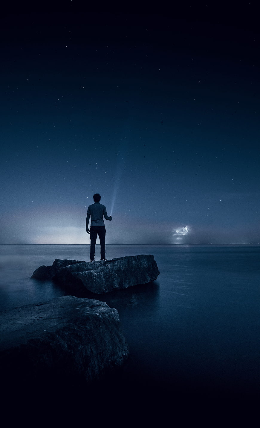 Man standing on rock looking at starry night sky