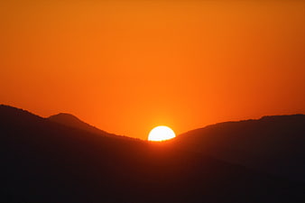 Vibrant Orange Sunset Silhouette Over Mountain Ridges