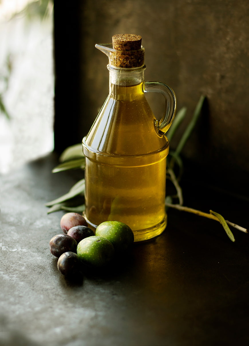 Glass Bottle of Olive Oil with Fresh Olives and Branches