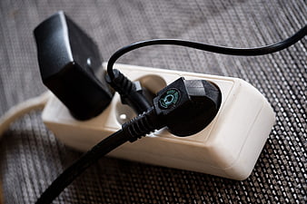 Close-up of black electrical plug connected to white power strip