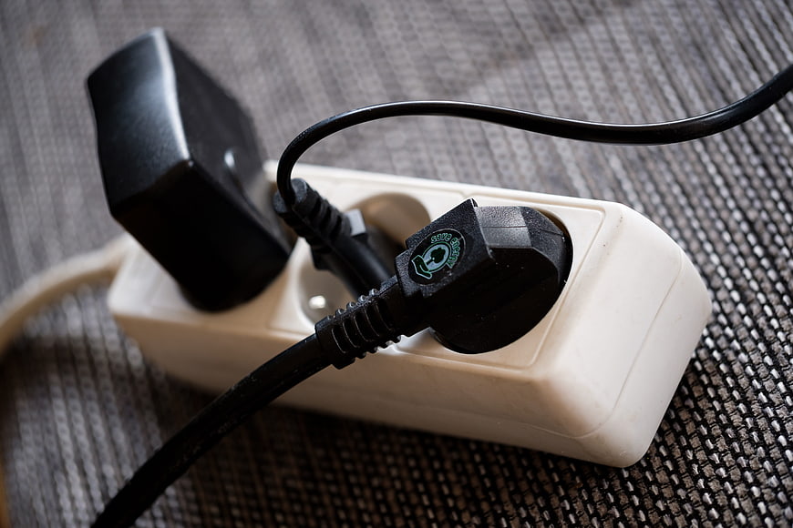 Close-up of black electrical plug connected to white power strip