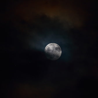 Full moon glowing through dark night clouds