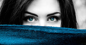 Close-up of woman with blue eyes peeking over blue fabric