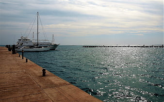 Luxury yacht docked at wooden pier with sparkling sea