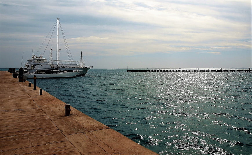 Luxury yacht docked at wooden pier with sparkling sea