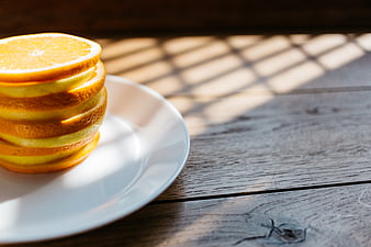 Stack of sliced oranges and lemons on a white plate
